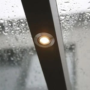 Integrierte LED-Beleuchtung in einer Terrassenüberdachung, bei regnerischem Wetter. Moderne Lichtlösung für eine stimmungsvolle Atmosphäre im Außenbereich.