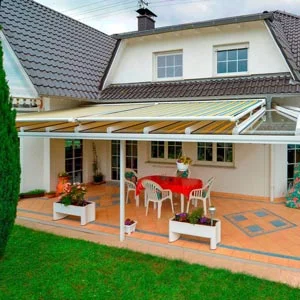 Terrassenüberdachung mit integrierter Markise an einem Einfamilienhaus, darunter ein Essbereich mit Tisch und Stühlen.